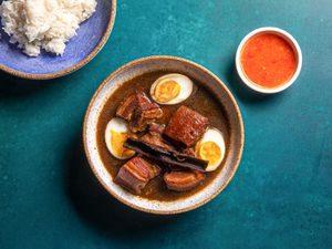 Overhead shot of finished moo palo with cut open eggs, dipping sauce, and a plate of rice
