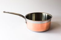 A metal saucepan with a smooth handle and a polished interior on a plain background