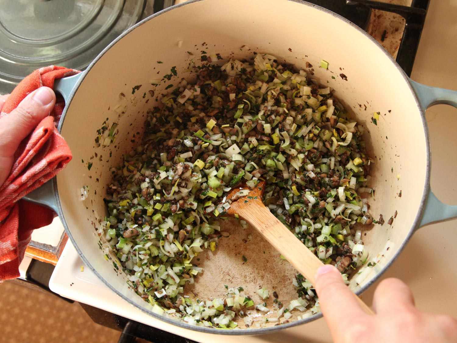 Chopped vegetables being sautéed inside of a Dutch oven.