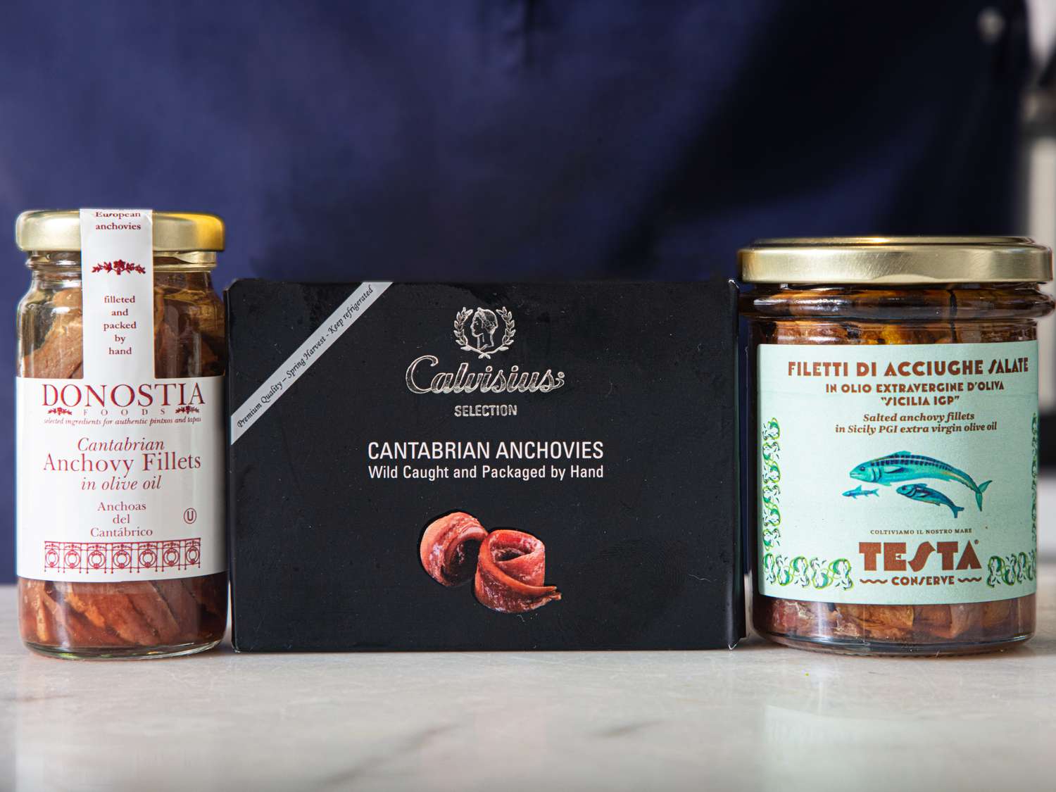 Three jars and a box of anchovies displayed on a surface