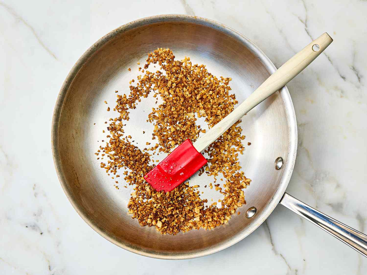 Sauteed ingredients in a skillet with a red spatula resting on the side