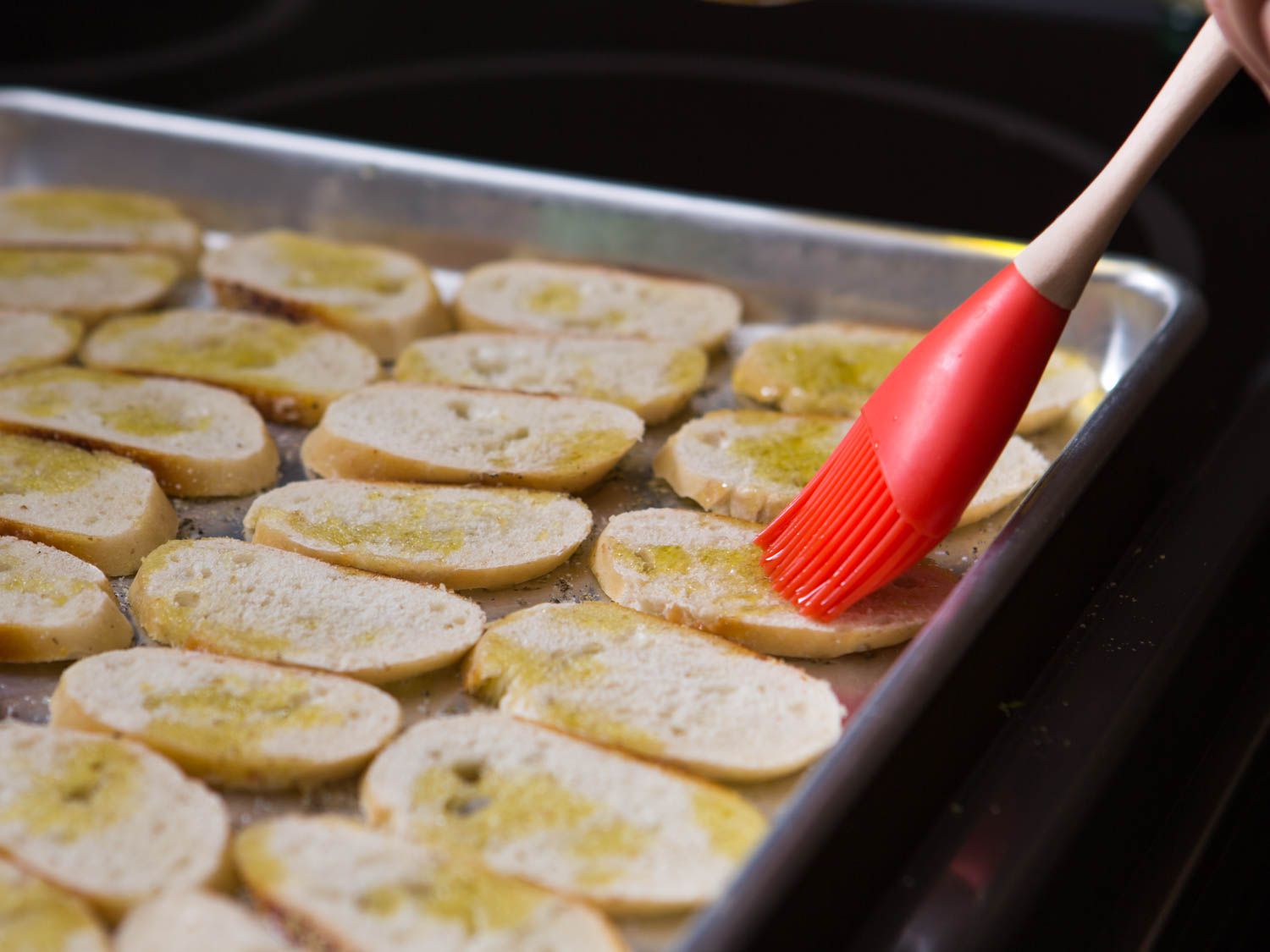 Brushing baguette slices with olive oil to make baguette crackers