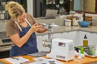 Person fixing food tray of STX International Turboforce Classic 3000 Series Electric Meat Grinder & Sausage Stuffer
