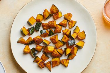 Roasted kabocha squash with soy sauce, butter, and shichimi togarashi on a white ceramic plate.