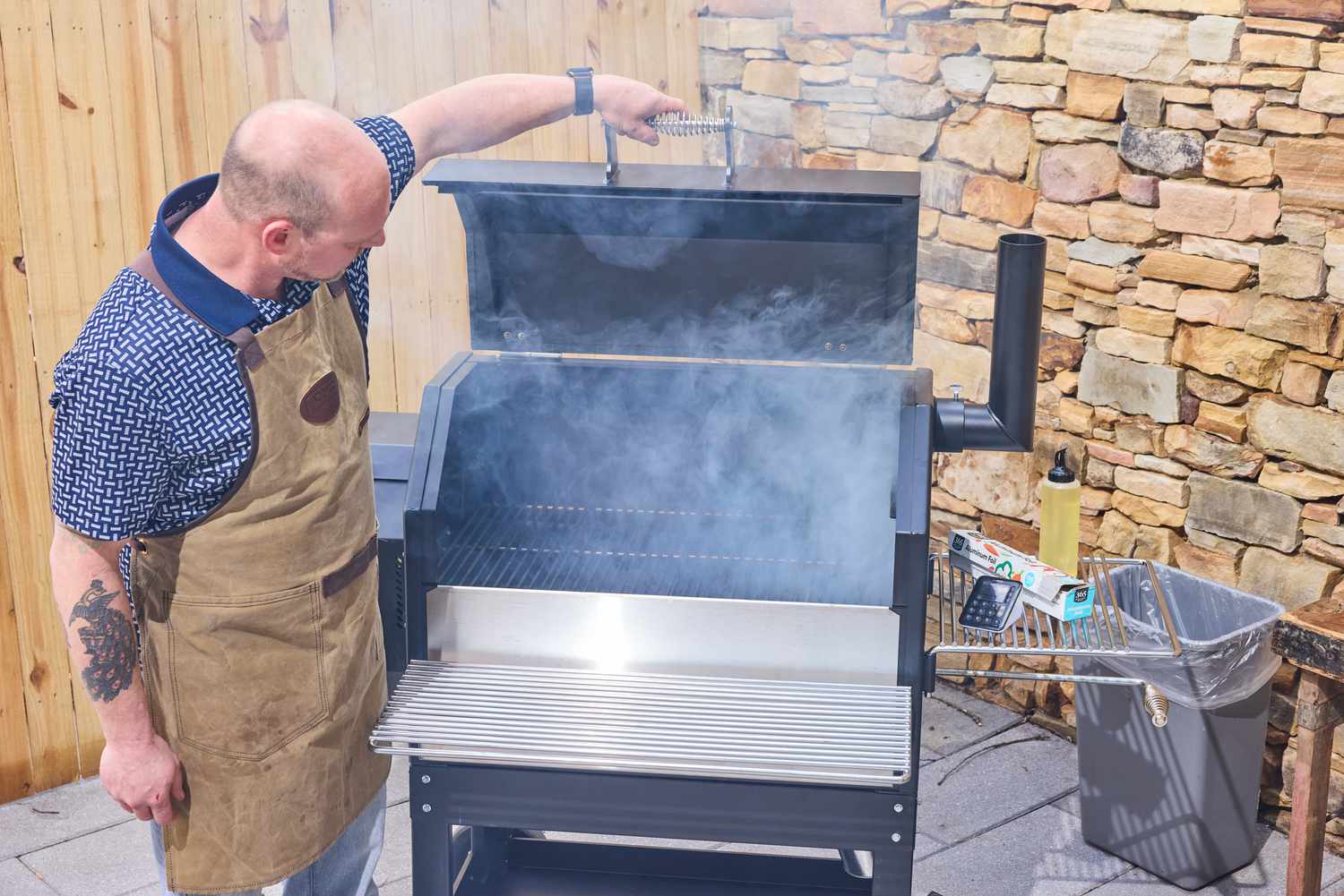 A person opens the lid on the Yoder Smokers YS640S Pellet Grill