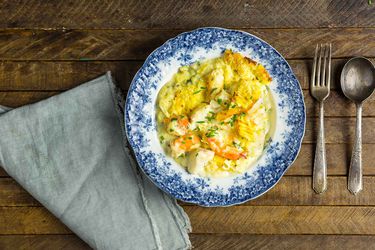  Overhead view of British Fish Pie With Smoked Salmon, Shrimp, and Mashed Potatoes, served on an antique porcelain plate.