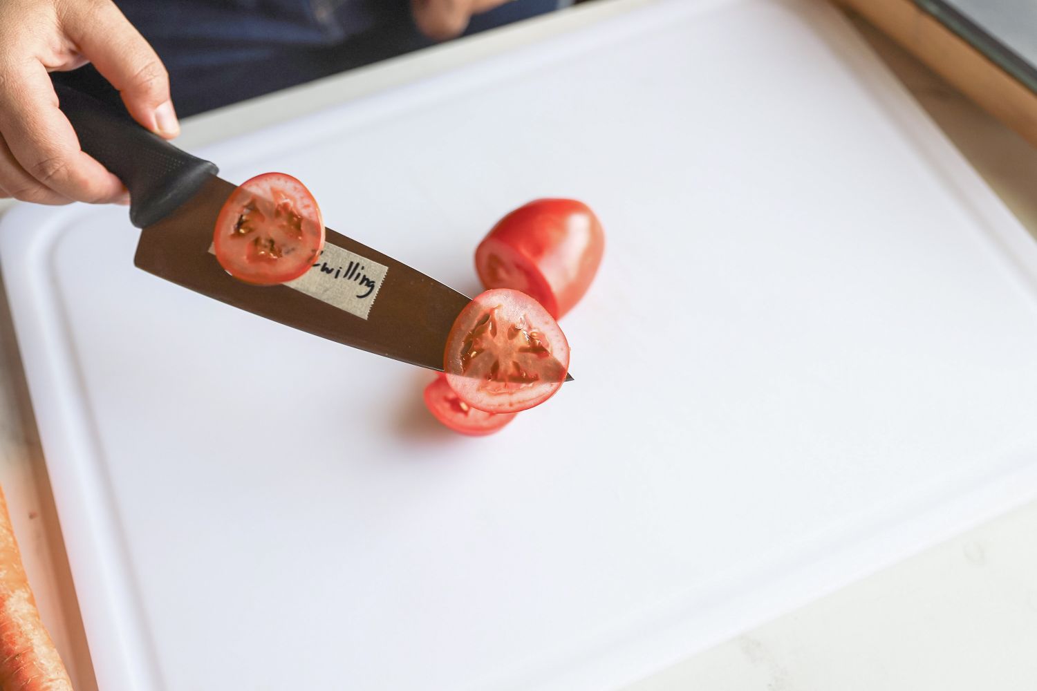 A person thinly slicing tomatoes with a knife
