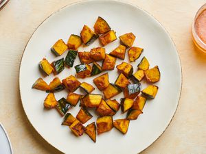 Roasted kabocha squash with soy sauce, butter, and shichimi togarashi on a white ceramic plate.