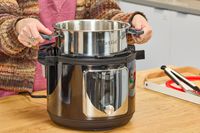 A person removes the inner pot from the Instant Pot Pro Plus Wi-Fi Smart 10-in-1 6-Quart Pressure Cooker