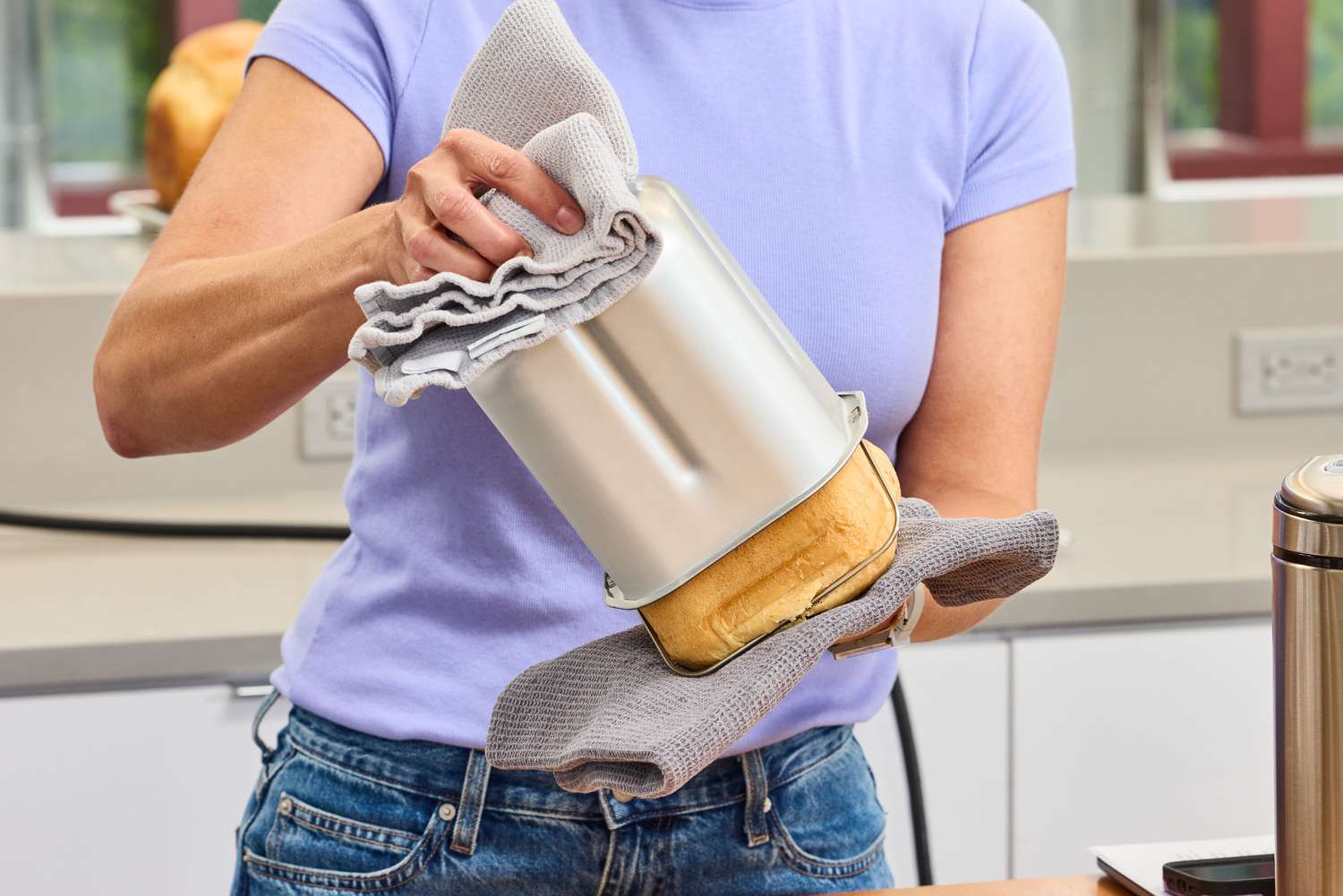 A person using two towels to remove bread from the Cuisinart CBK-110 Compact Automatic Bread Maker basket