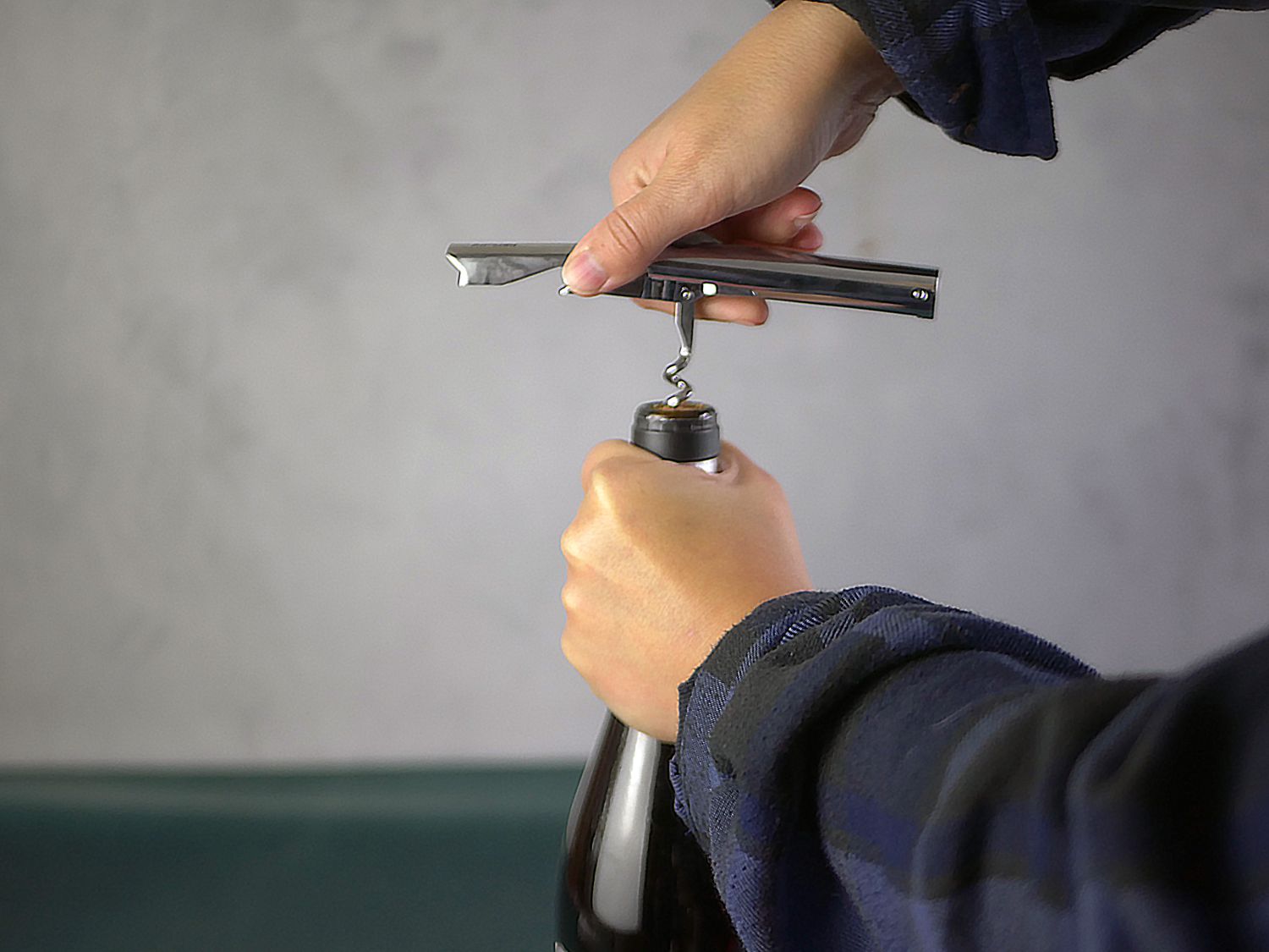 Using a metal wine opener to ppen a bottle of wine