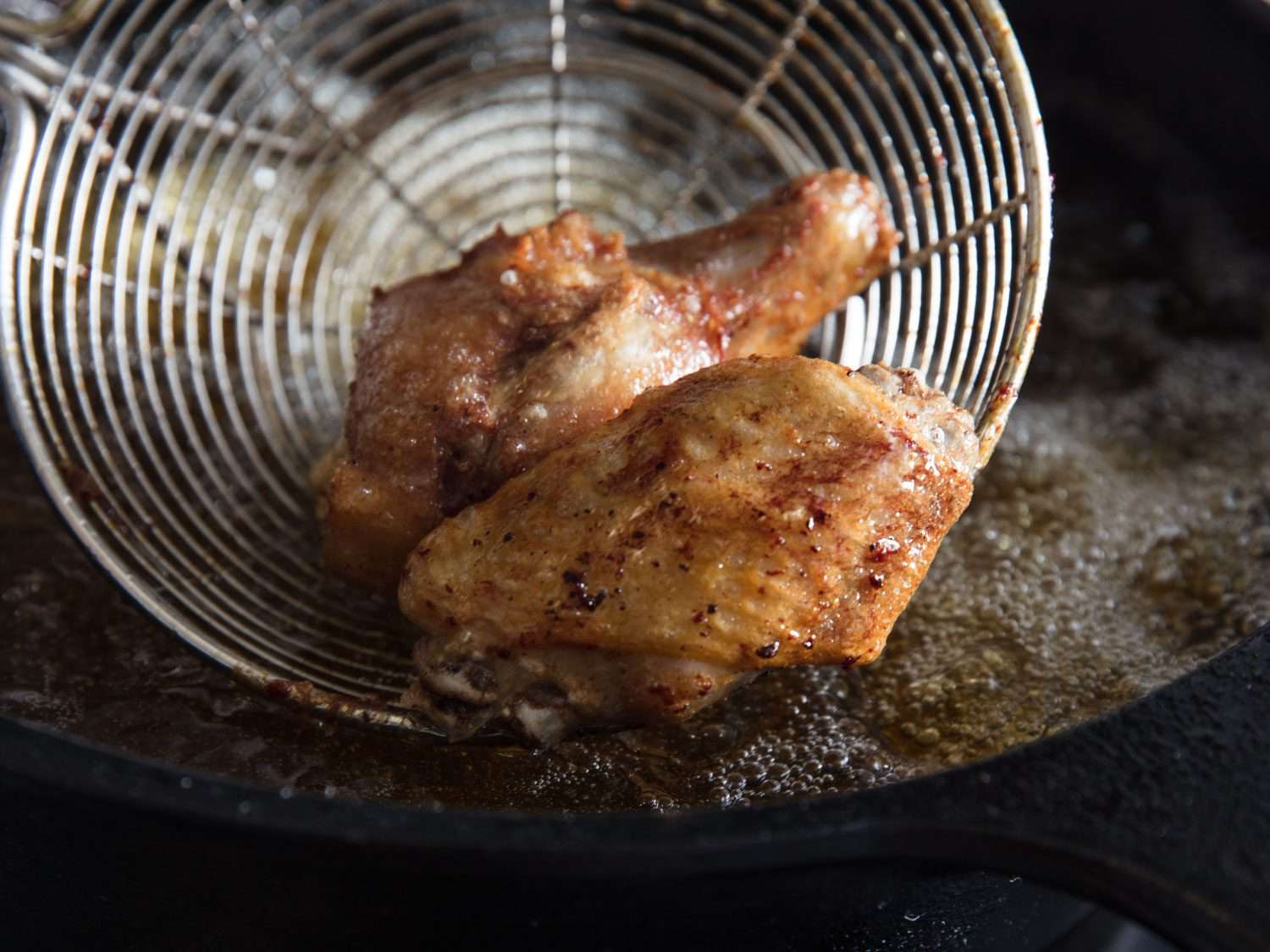 Sous vide chicken wings being crisped in hot oil.