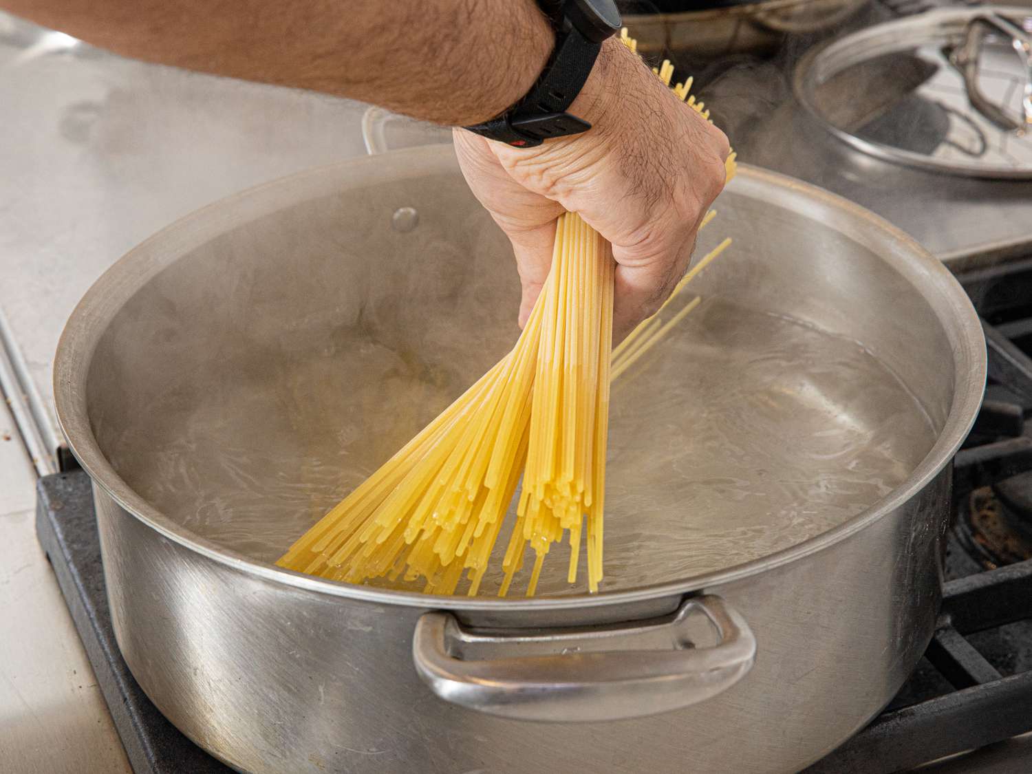 Side view of adding spaghetti to boiling water