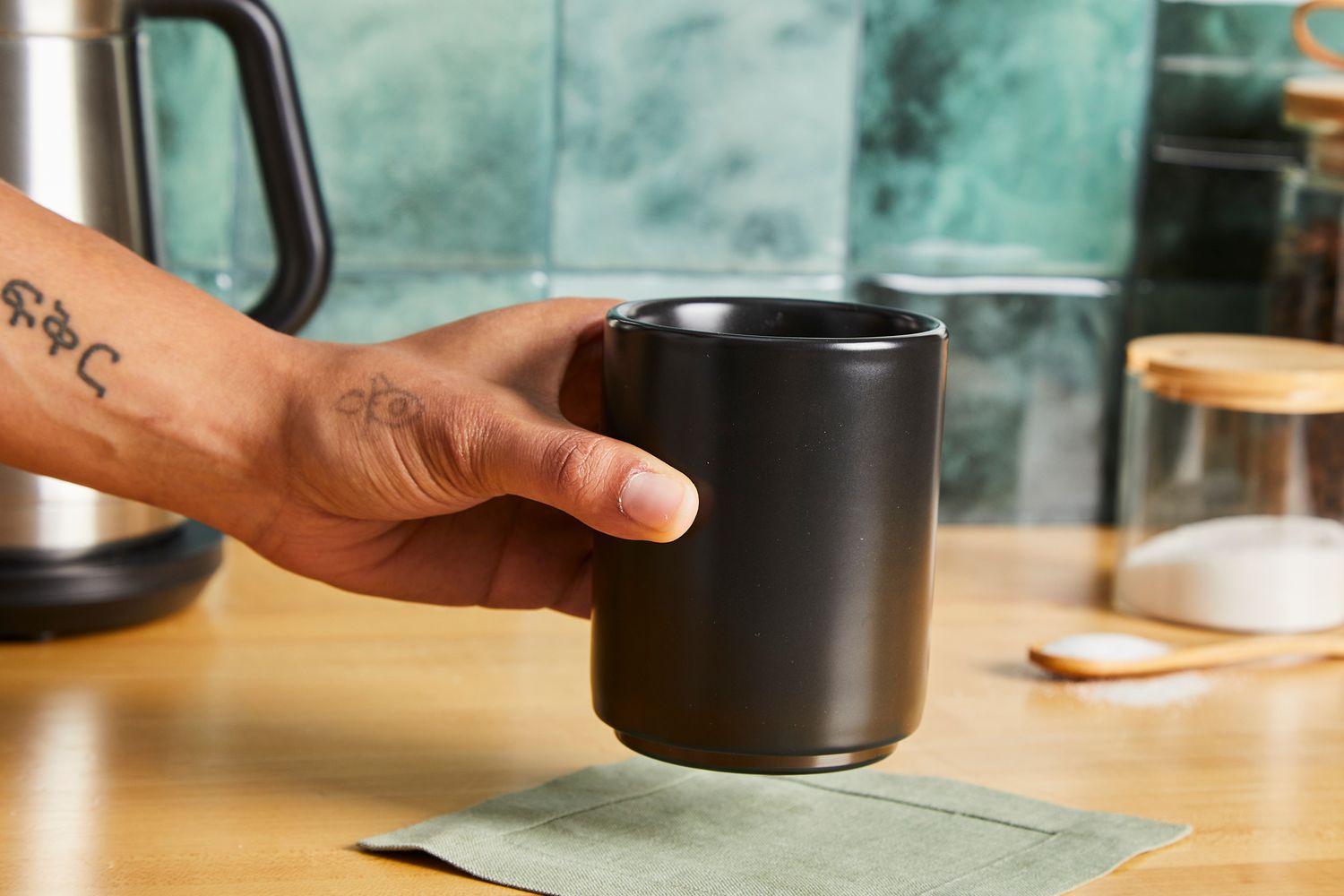 A person picking up the Fellow coffee mug.