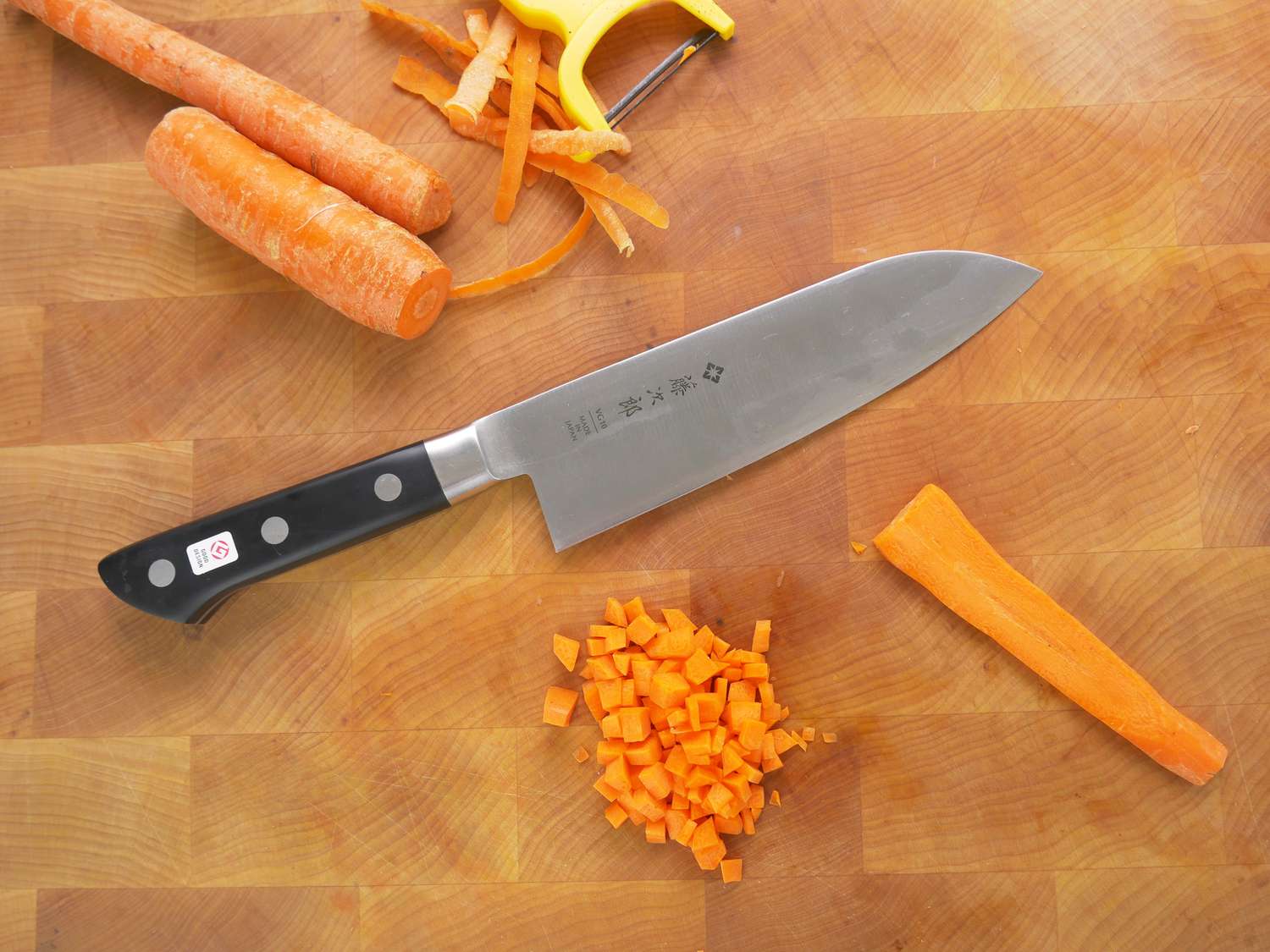 tojiro santoku on a cutting board with a cubed carrot