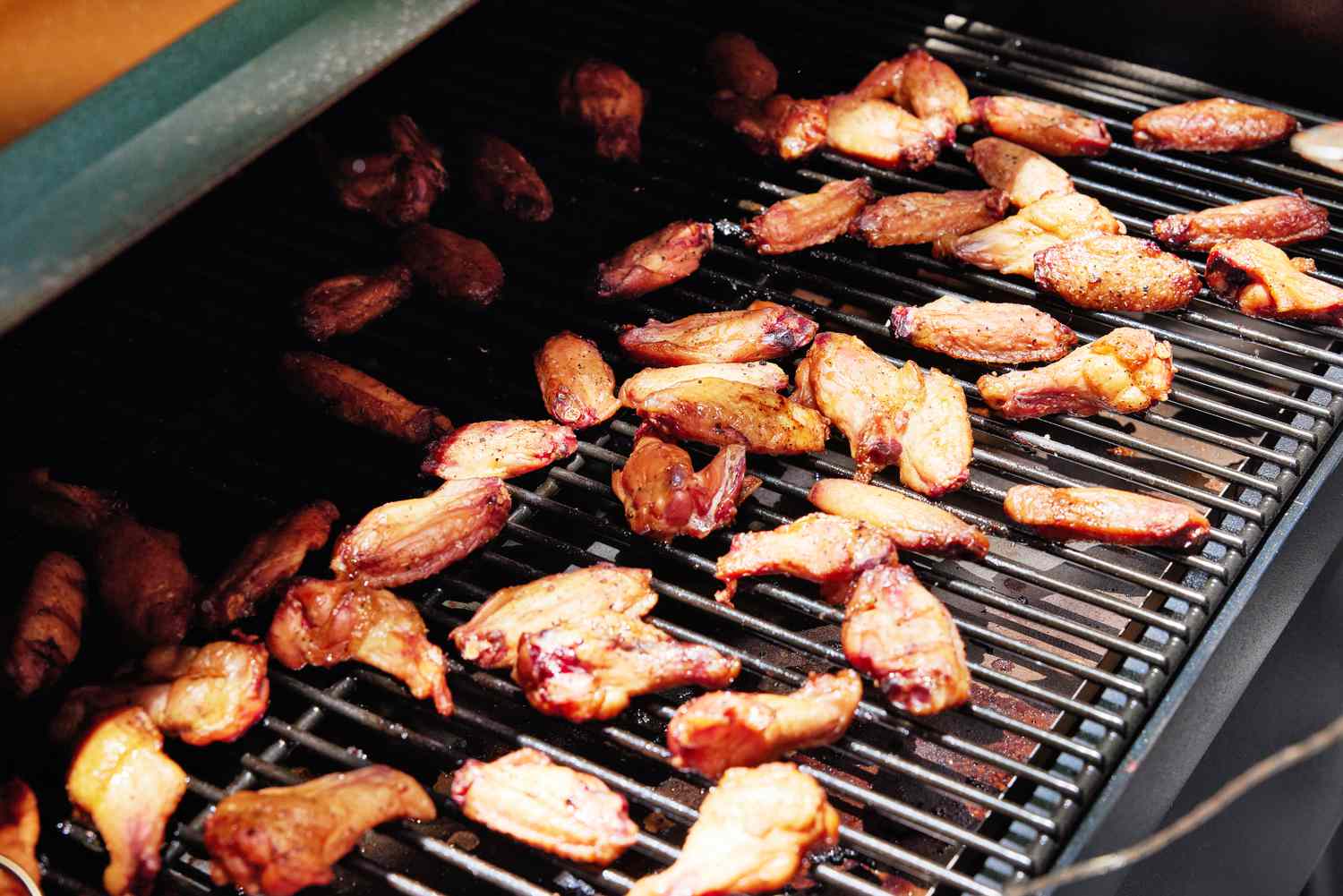 A closeup of cooked chicken wings on a pellet grill's grates