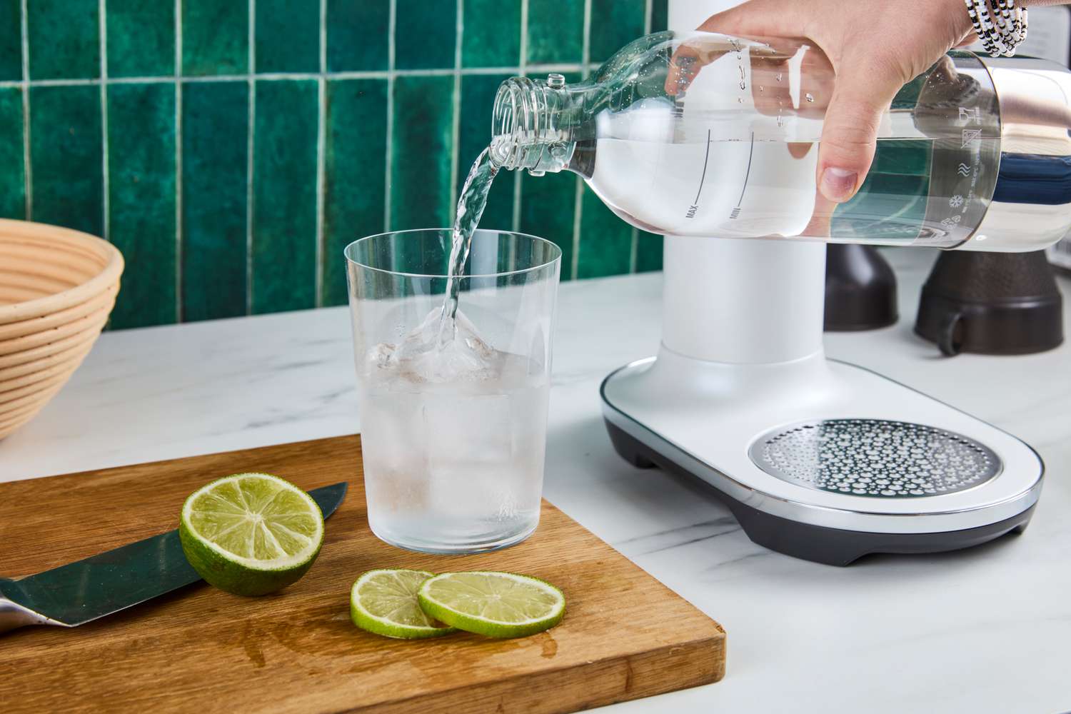 Sparkling water being poured from a soda maker bottle into a glass. 