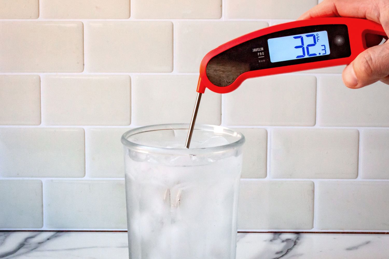 A person using the Lavatools thermometer to take the temperature of ice water.