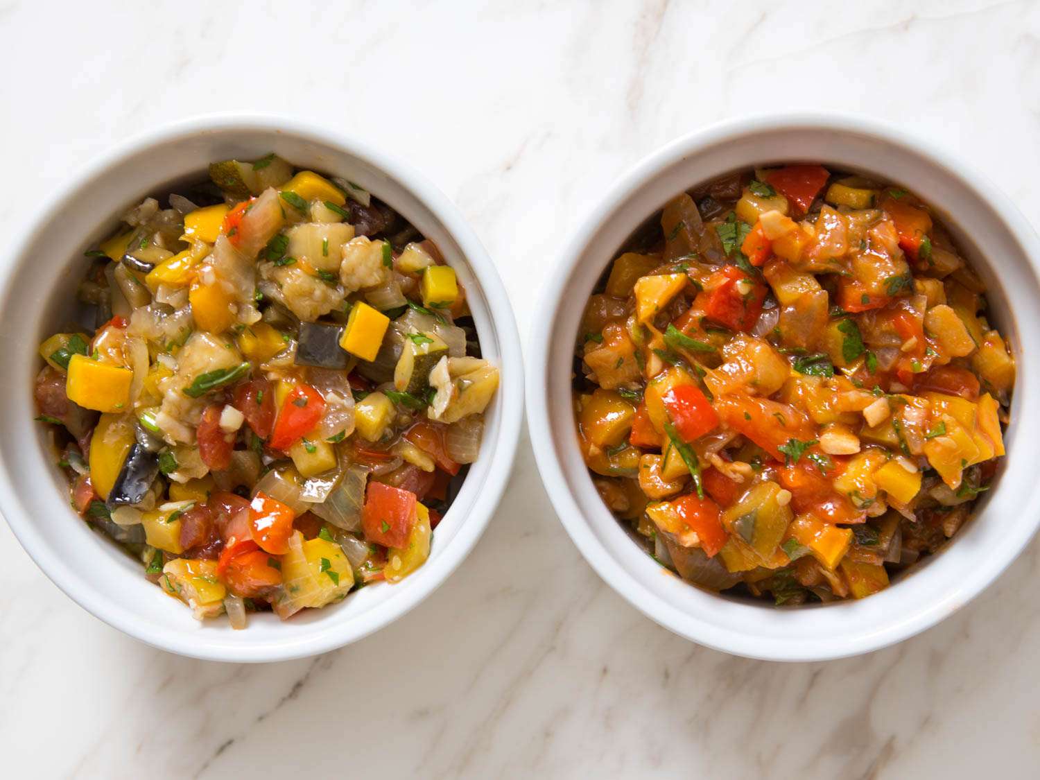 Two ramekins holding batches of ratatouille made with fresh tomatoes and puréed tomatoes, respectively. The fresh-tomato batch is not nearly as red or as saucy.