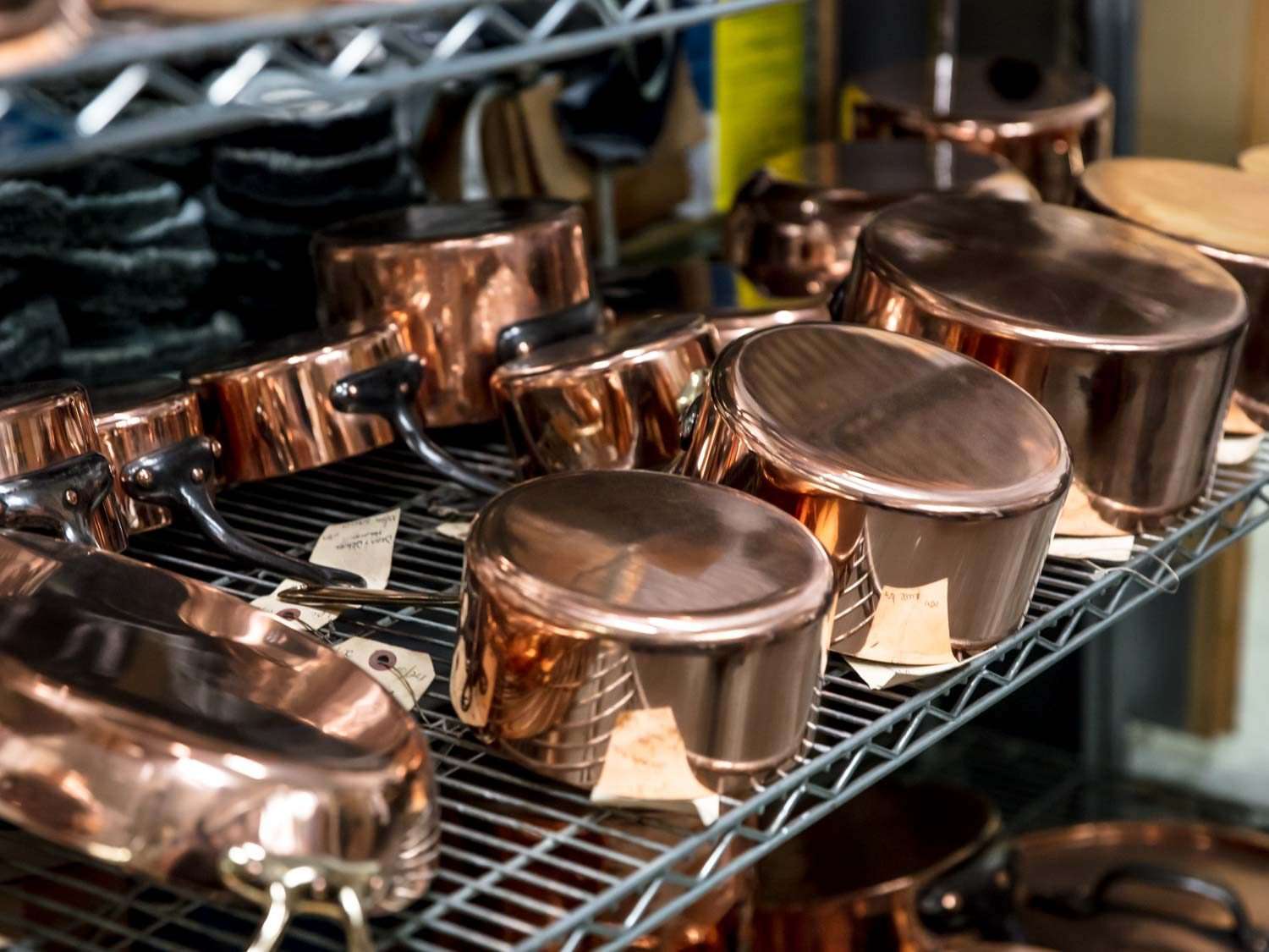 Copper cookware on a metal shelf.