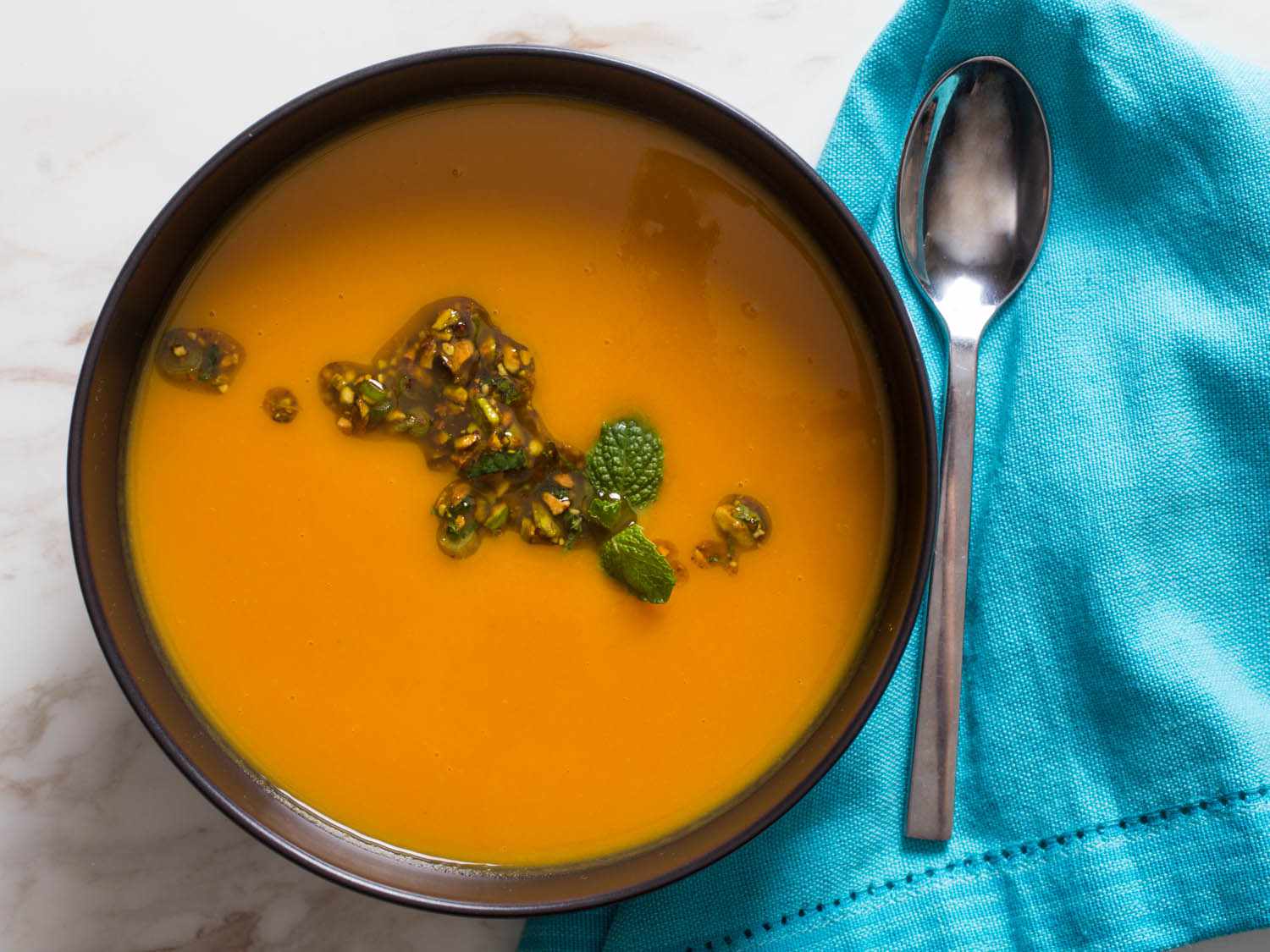 A bowl of sweet potato orange soup, topped with pistachio salsa. 