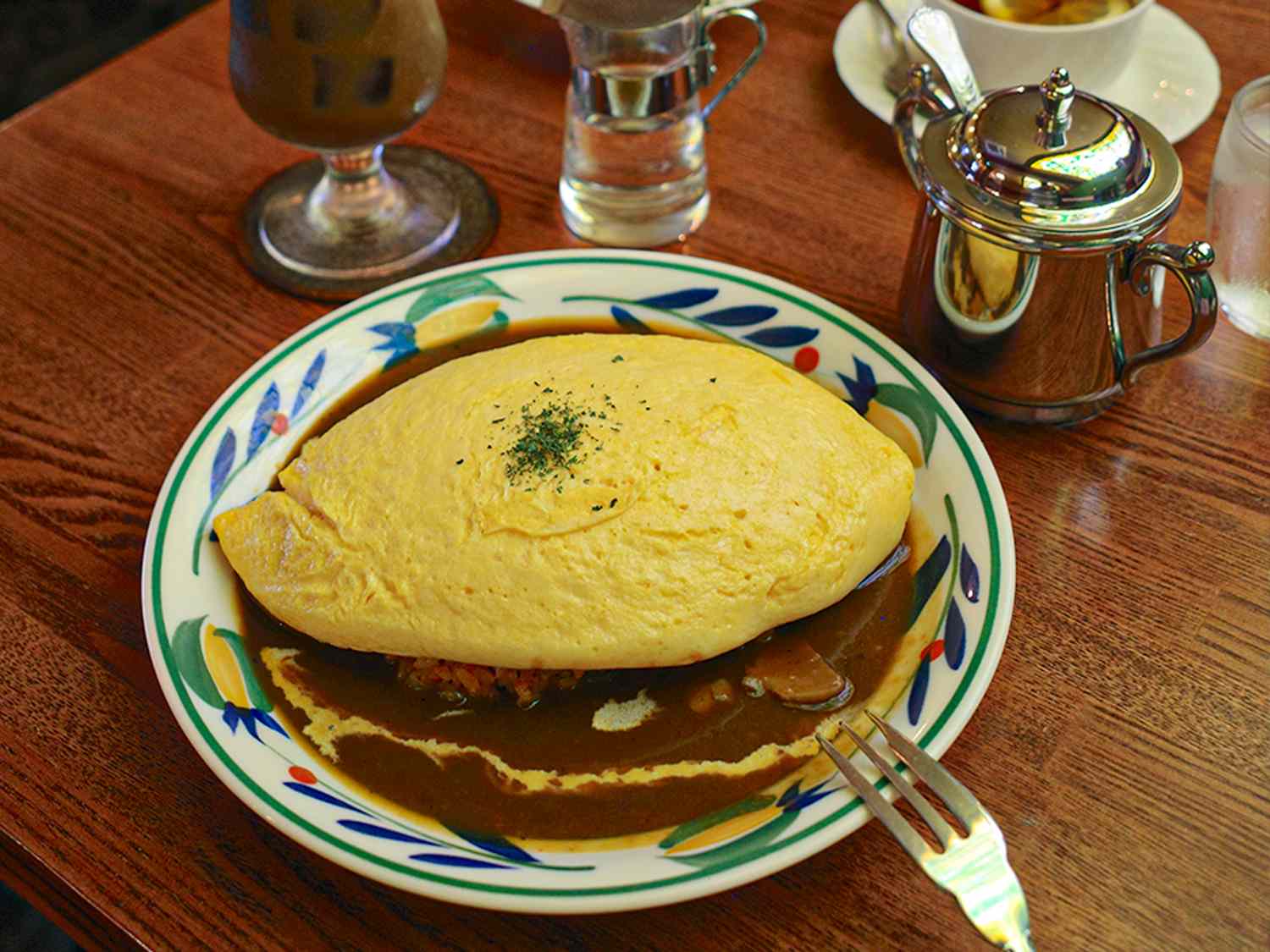A dish consisting of an omurice drizzled with sauce served on a decorative plate