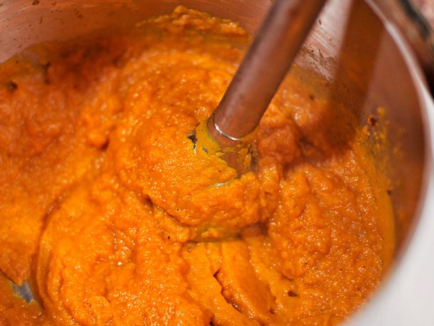 An immersion blender pureeing butternut squash mixture until smooth. 