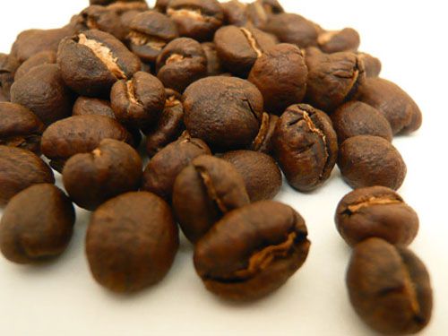 A pile of peaberry beans on a white surface.