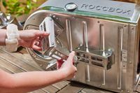 Two hands holding a metal part on the Gozney Roccbox Pizza Oven