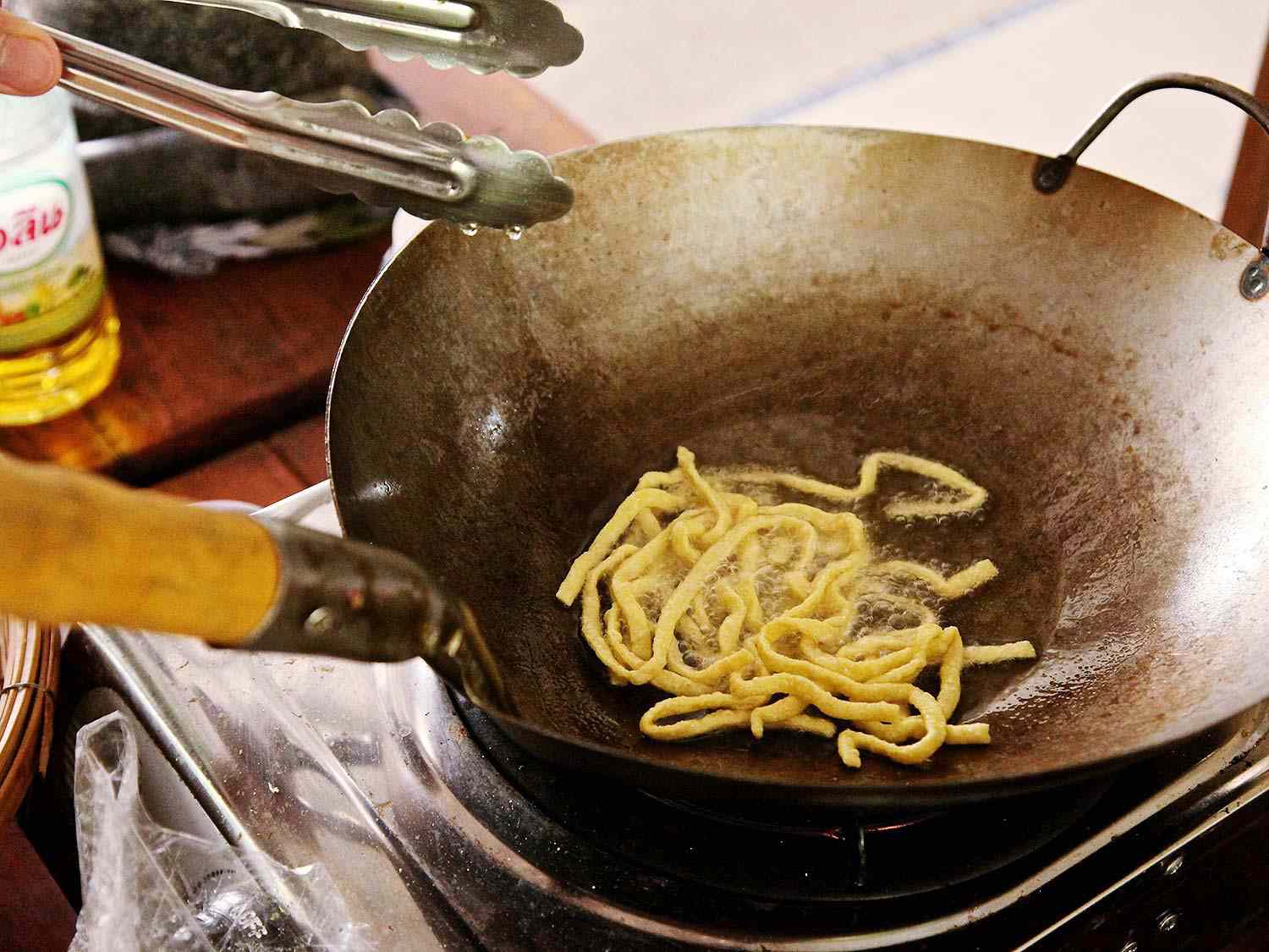 Egg noodles being fried in a wok at Small House Thai Cooking School.
