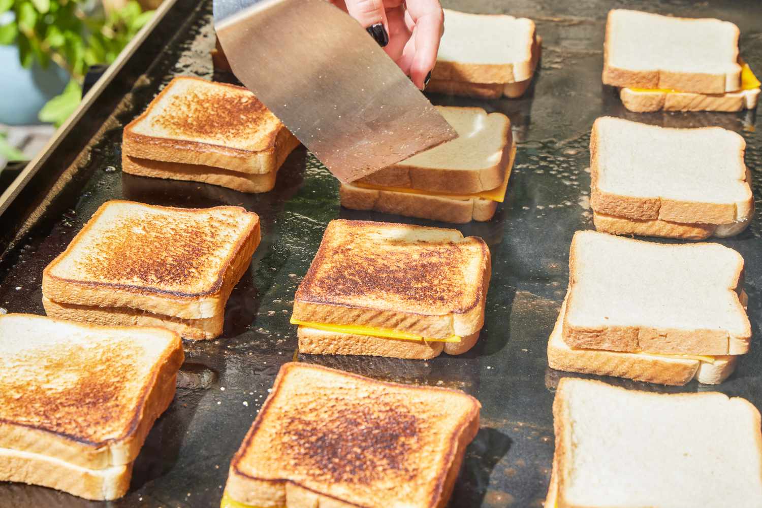 A person makes grilled cheese on the Weber 36 Inch Gas Griddle