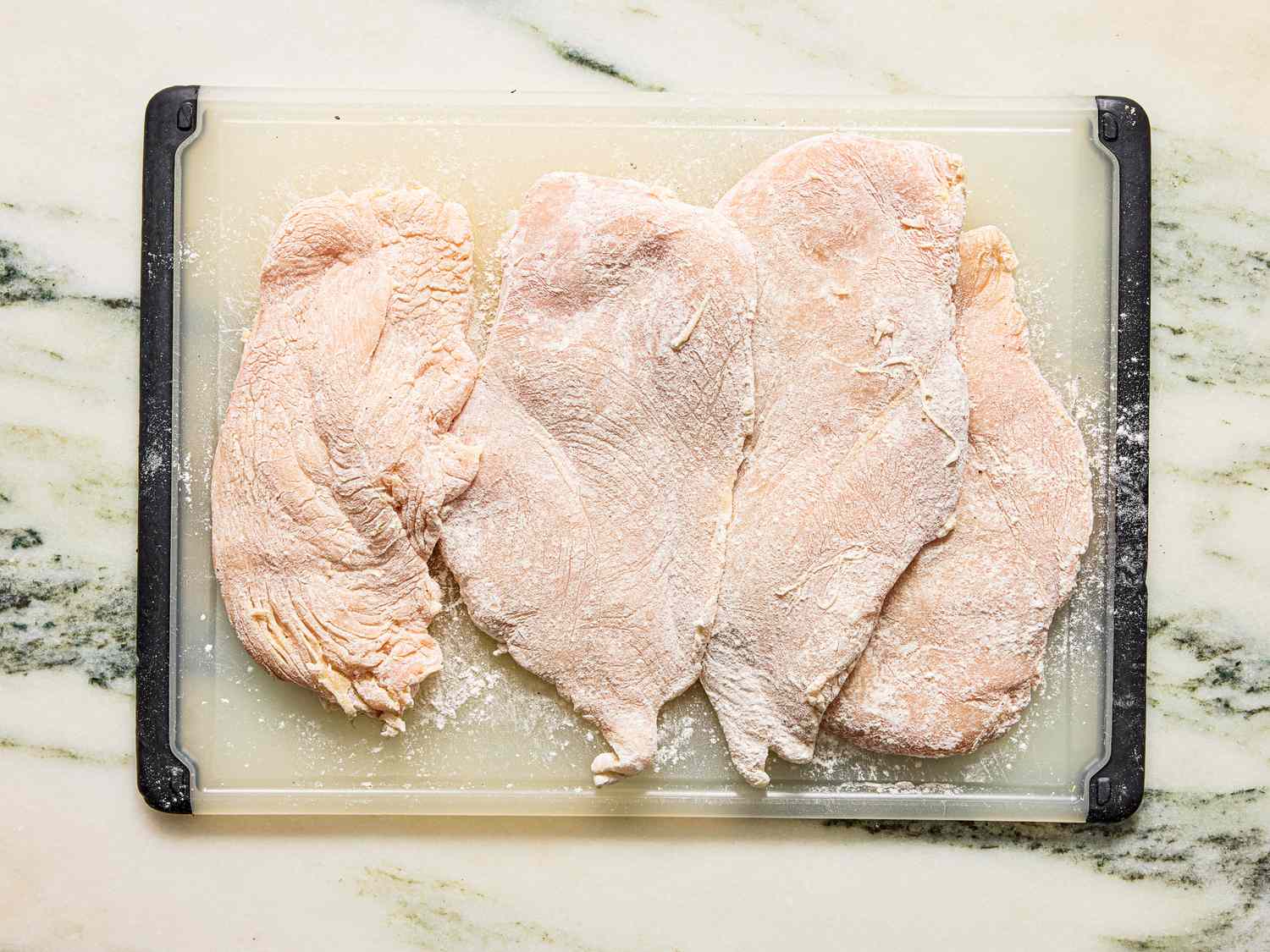 Flattened chicken fillets prepared on a cutting board