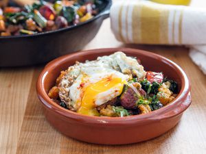 A bowl of migas topped with a fried egg with a runny yolk.