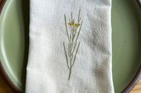 A cloth napkin with a floral design folded on a plate