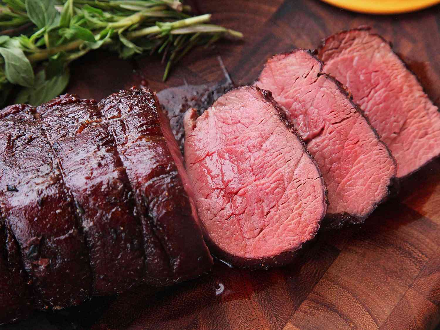 Sliced beef tenderloin on a cutting board.