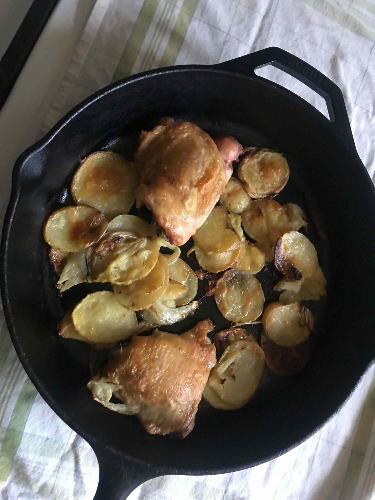 Chicken thighs and sliced potatoes and fennel in a cast iron pan