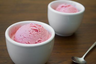 Scoops of strawberry frozen yogurt served in small white ceramic cups.