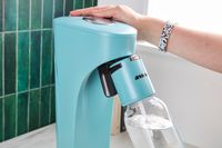 A person carbonating water with the Drinkmate soda maker.