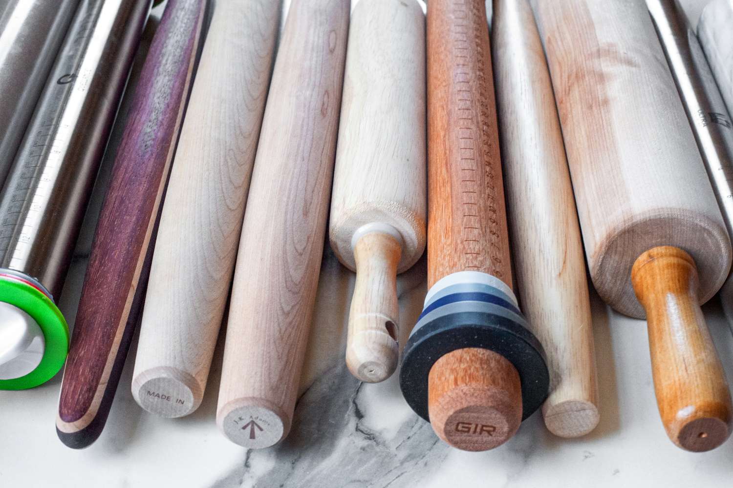 A collection of rolling pins displayed on a flat surface showing various designs and materials
