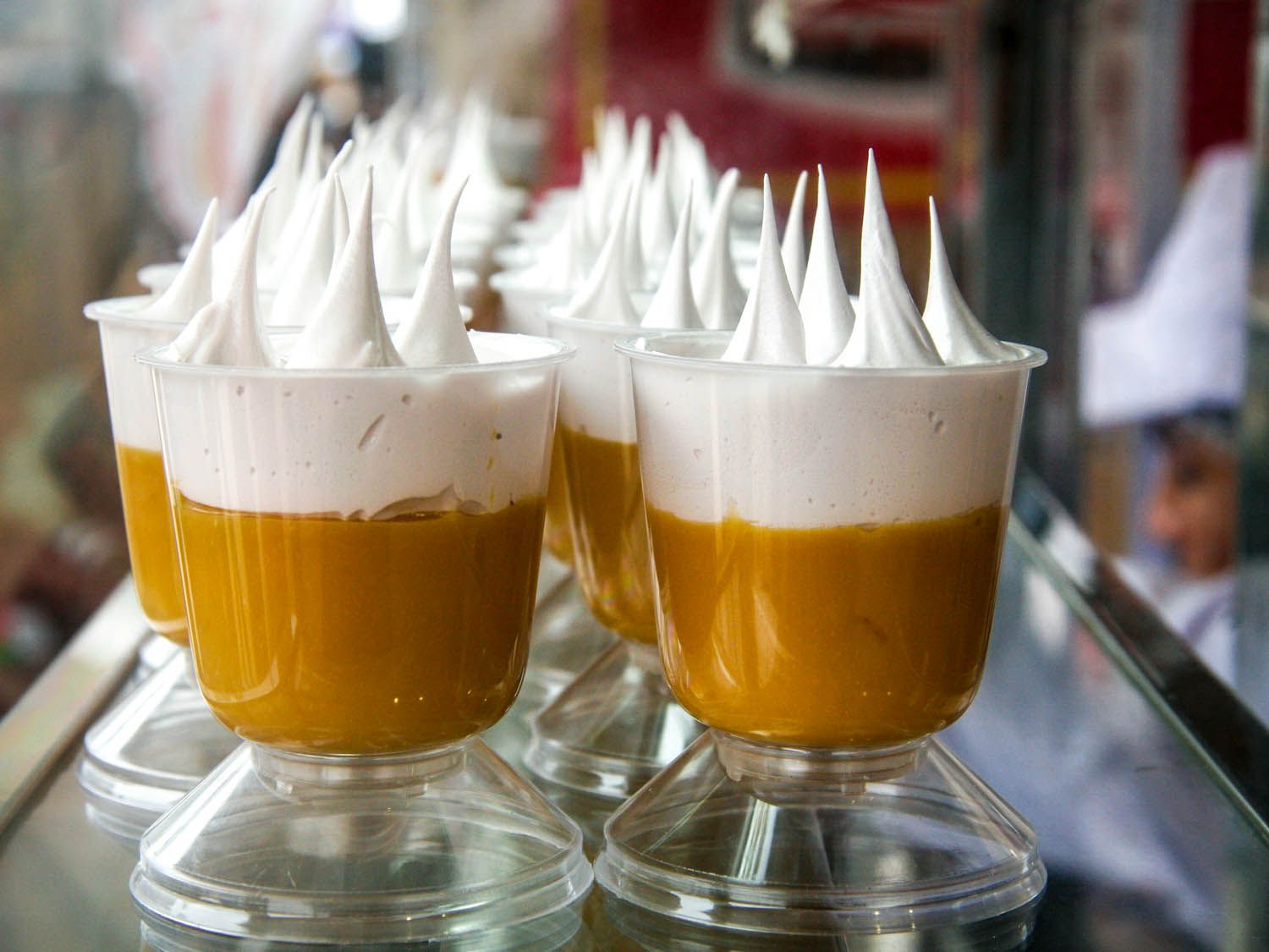 Peruvian suspiro limeño lined up in glass dishes. It has two layers with the top one whipped into peaks.