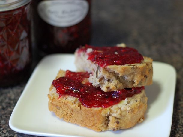 Two slices of bread topped with apple blackberry jam, with two pint jars just behind.