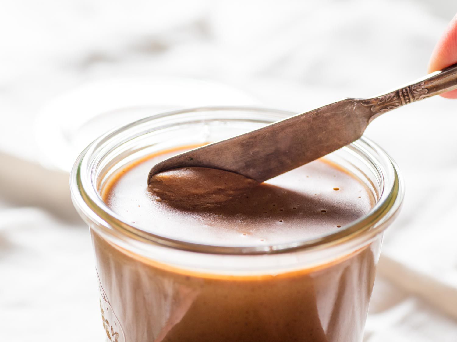 Butter knife in a jar of brown cookie butter.
