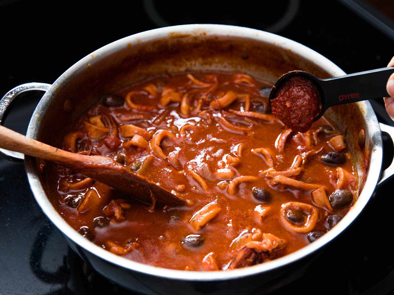 Harissa is spooned into the tomato braised squid.