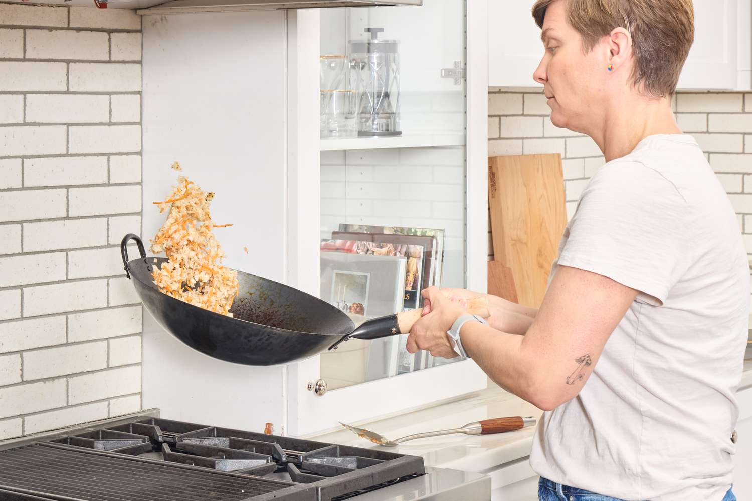 A person tosses fried rice in the Mammafong Pre-Seasoned Blue Carbon Steel Flat-Bottom Pow Wok