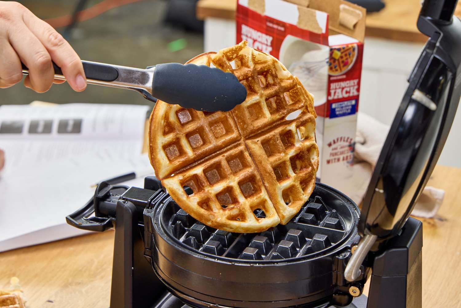 A person removes a waffle from the Black+Decker Double Flip Rotating Waffle Maker 