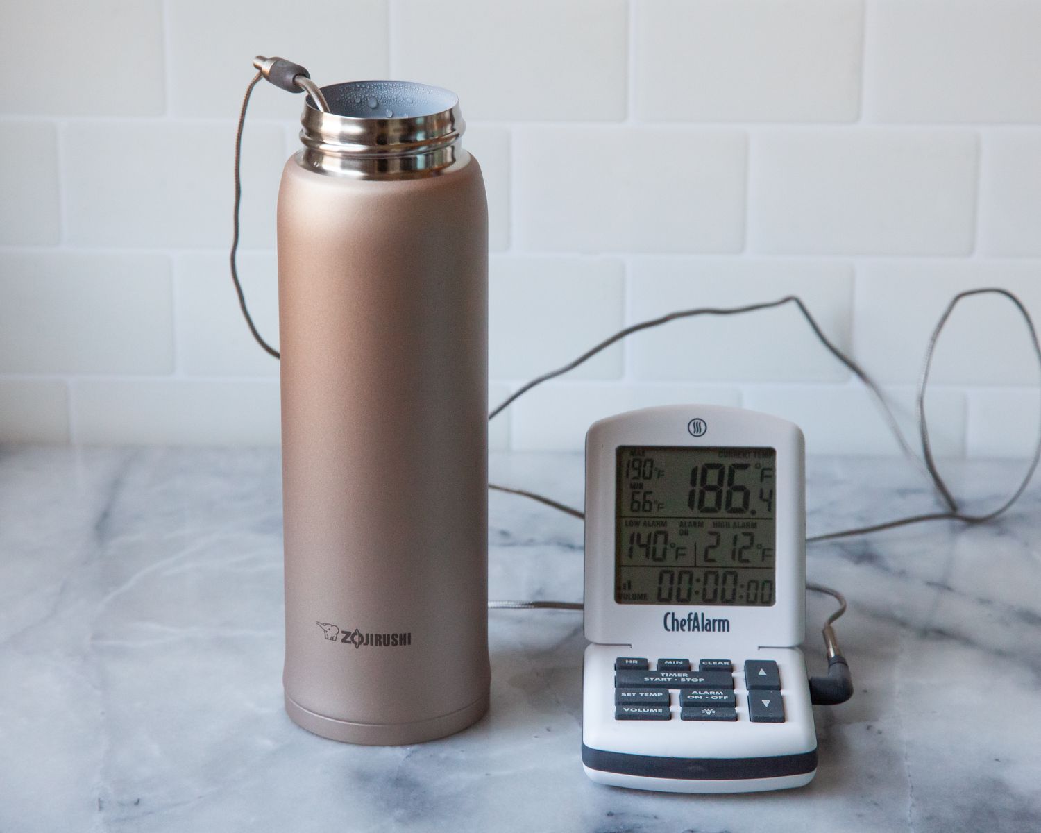 A probe thermometer's probe in a stainless steel travel mug.