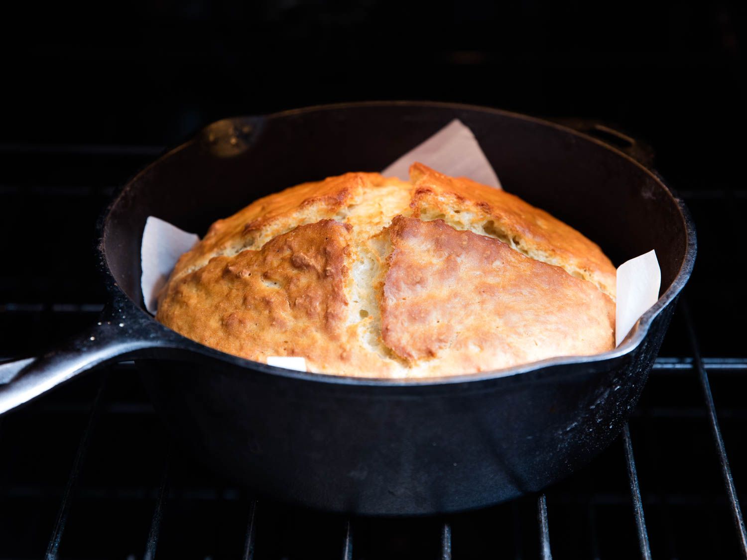 Irish soda bread in a parchment-lined cast iron skillet in the oven.
