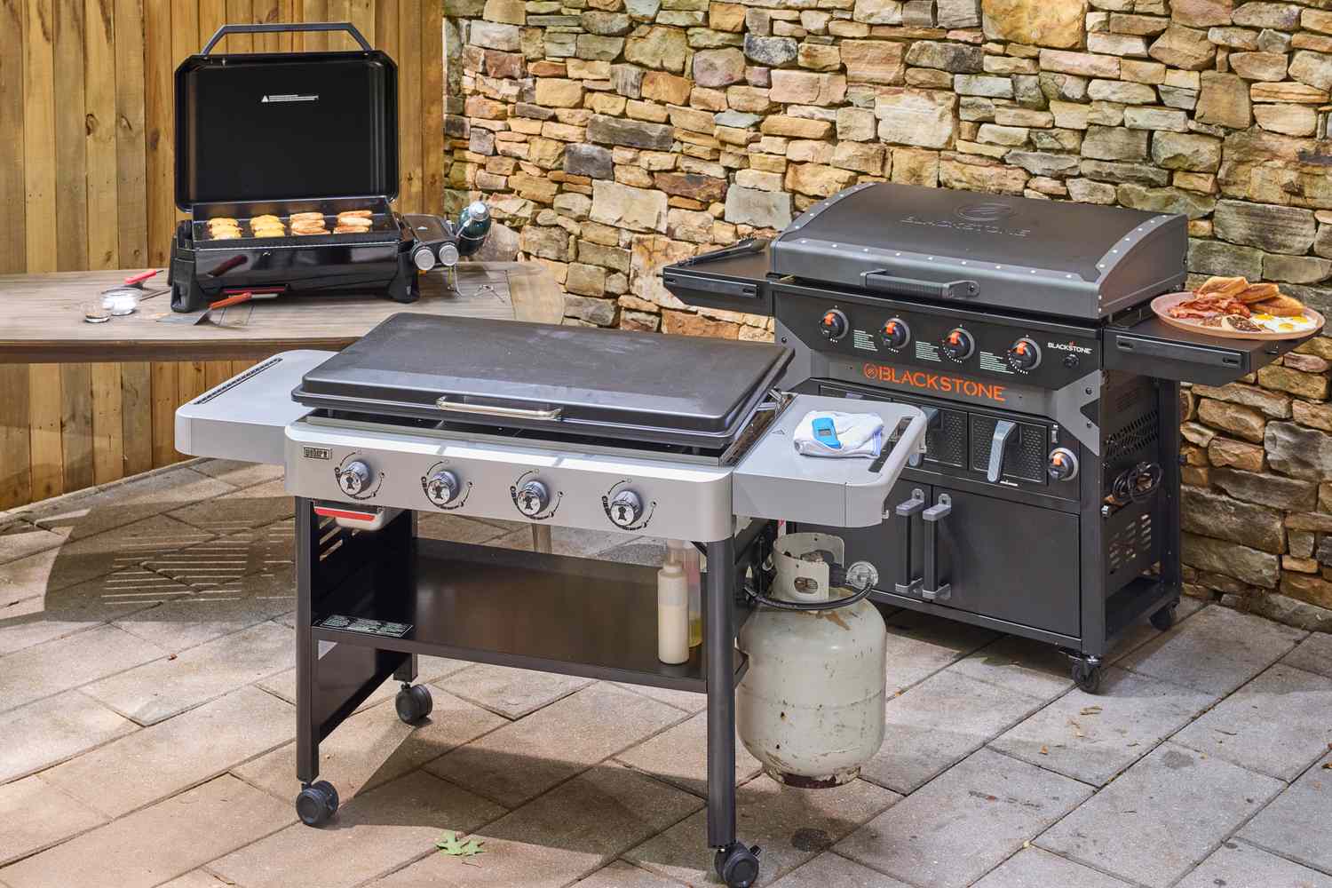 Three flat-top grills on an outdoor patio. 