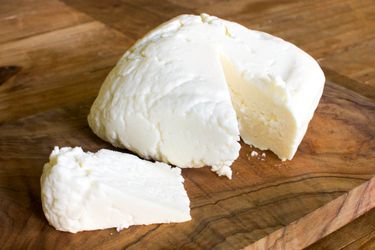 A cut of queso fresco resting on a cutting board