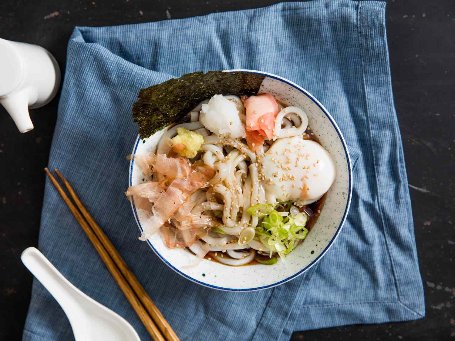 A bowl of chilled bukkake udon soup with a variety of toppings.